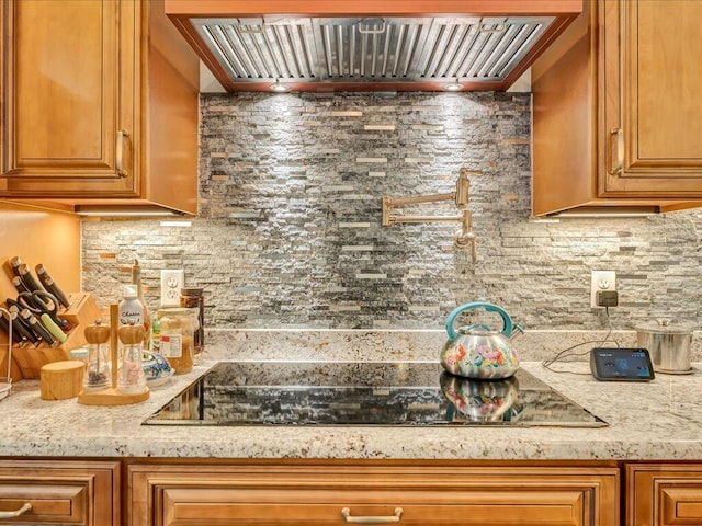 kitchen with decorative backsplash, light stone countertops, and wall chimney range hood