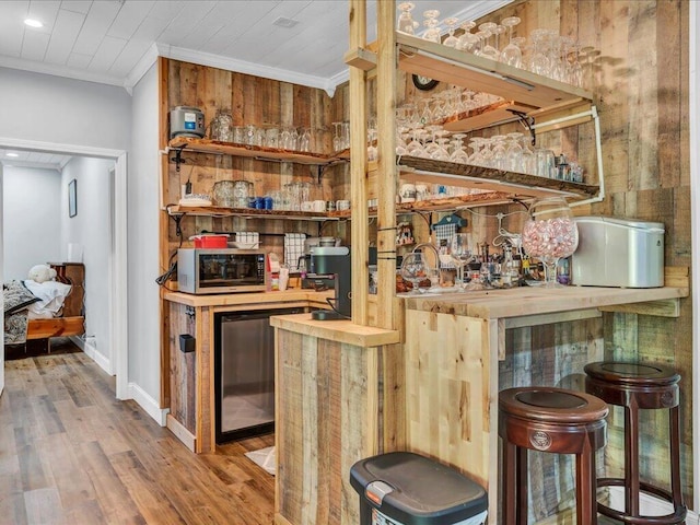 bar featuring light hardwood / wood-style floors, crown molding, and wooden counters