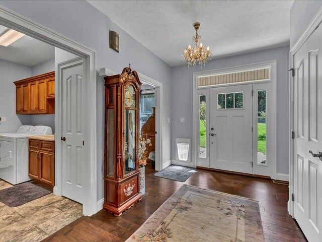 foyer with a notable chandelier, dark hardwood / wood-style floors, and washer / clothes dryer