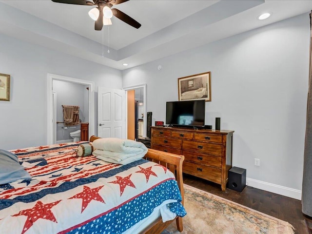 bedroom featuring ceiling fan, dark hardwood / wood-style flooring, connected bathroom, and a tray ceiling