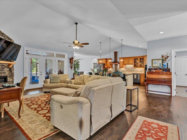 living room with ceiling fan, french doors, dark wood-type flooring, lofted ceiling, and a fireplace