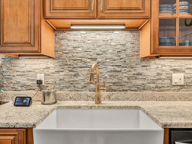 kitchen featuring light stone countertops, backsplash, and sink