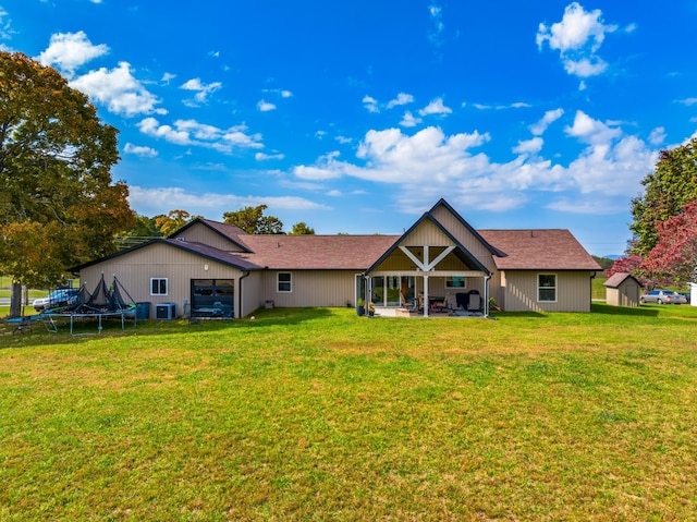 rear view of property with central air condition unit, a yard, a patio, and a trampoline