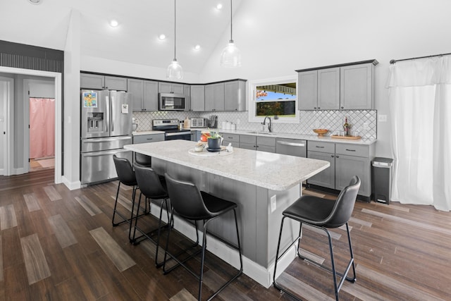 kitchen with appliances with stainless steel finishes, pendant lighting, high vaulted ceiling, a center island, and a breakfast bar area