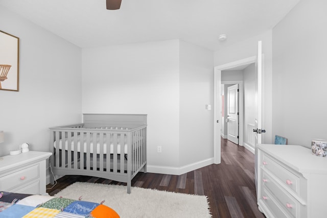 bedroom featuring ceiling fan, dark hardwood / wood-style floors, and a crib