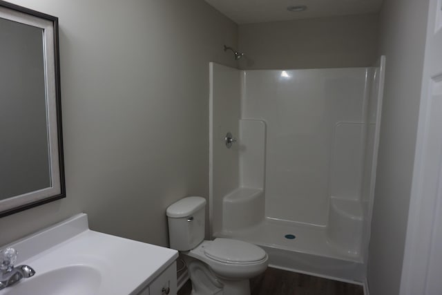 bathroom with a shower, hardwood / wood-style floors, vanity, and toilet