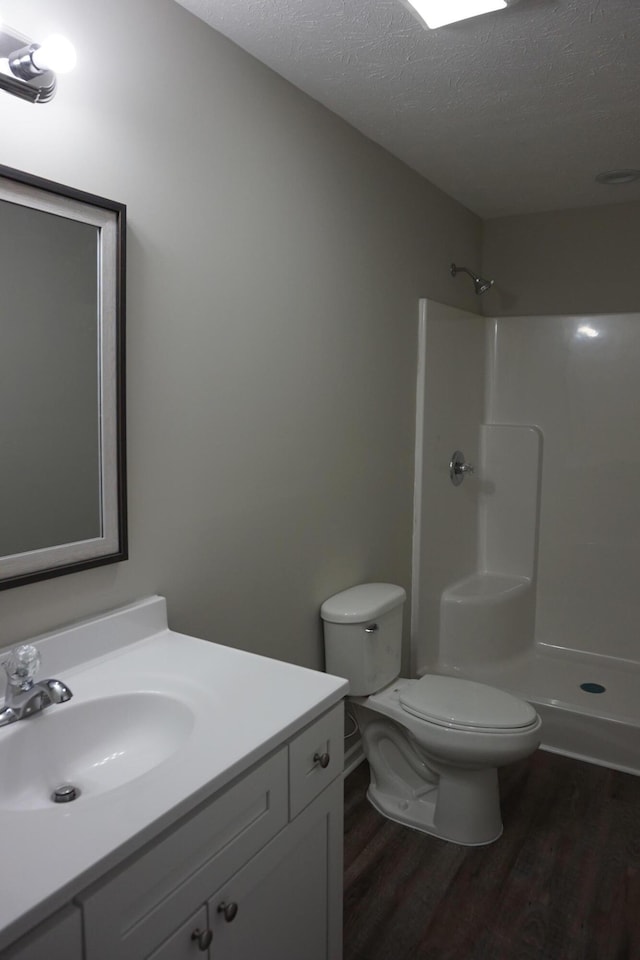 bathroom with a shower, toilet, a textured ceiling, and hardwood / wood-style flooring