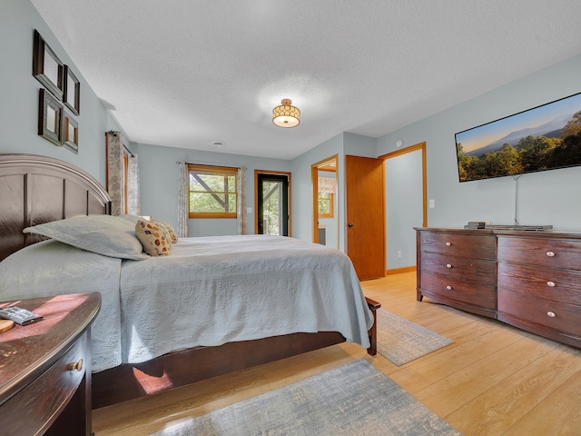 bedroom with light wood-type flooring and a textured ceiling