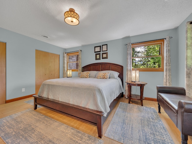 bedroom featuring a textured ceiling, baseboards, wood finished floors, and a closet