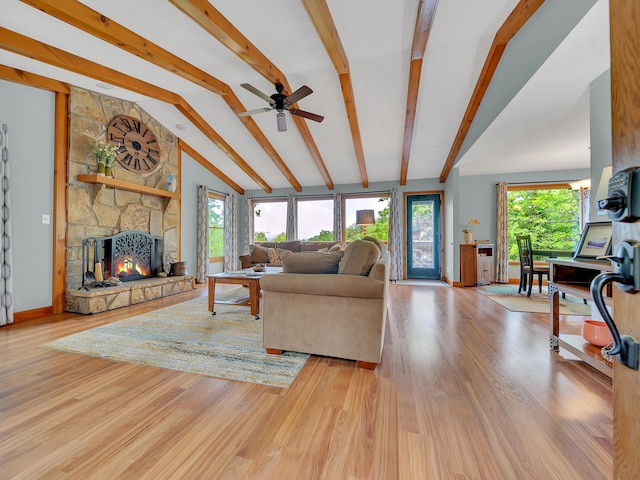 living area with a stone fireplace, wood finished floors, and a ceiling fan