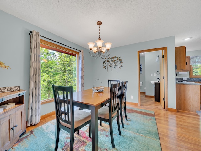 dining area featuring a chandelier, light wood-style floors, plenty of natural light, and a textured ceiling