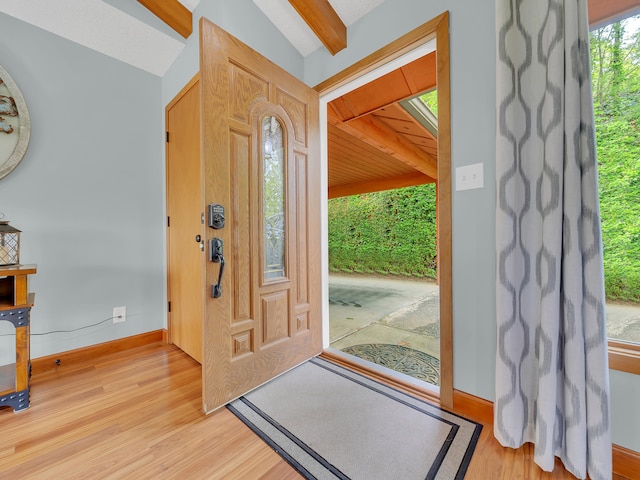 foyer entrance featuring light wood-style floors, baseboards, and beamed ceiling