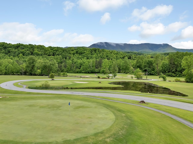 view of community with a mountain view, golf course view, and a lawn