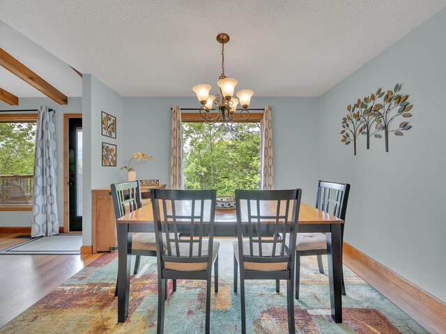 dining area featuring a chandelier, wood finished floors, a textured ceiling, and baseboards