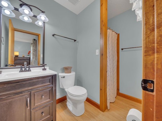 bathroom with wood finished floors, toilet, vanity, and baseboards