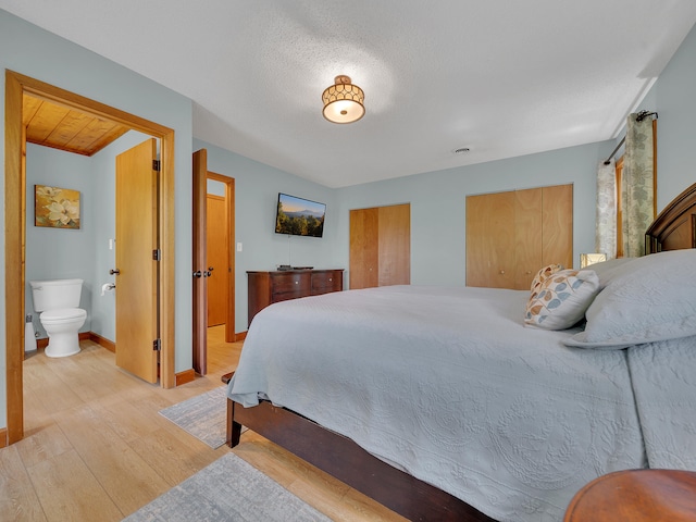 bedroom with light wood-type flooring, two closets, baseboards, and connected bathroom