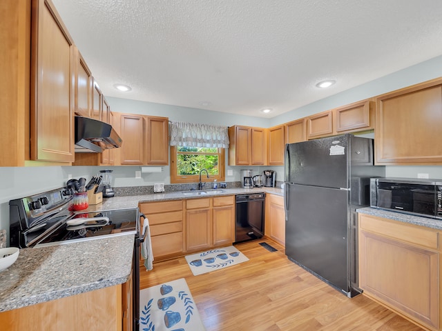 kitchen featuring black appliances, under cabinet range hood, a sink, light wood-type flooring, and a textured ceiling