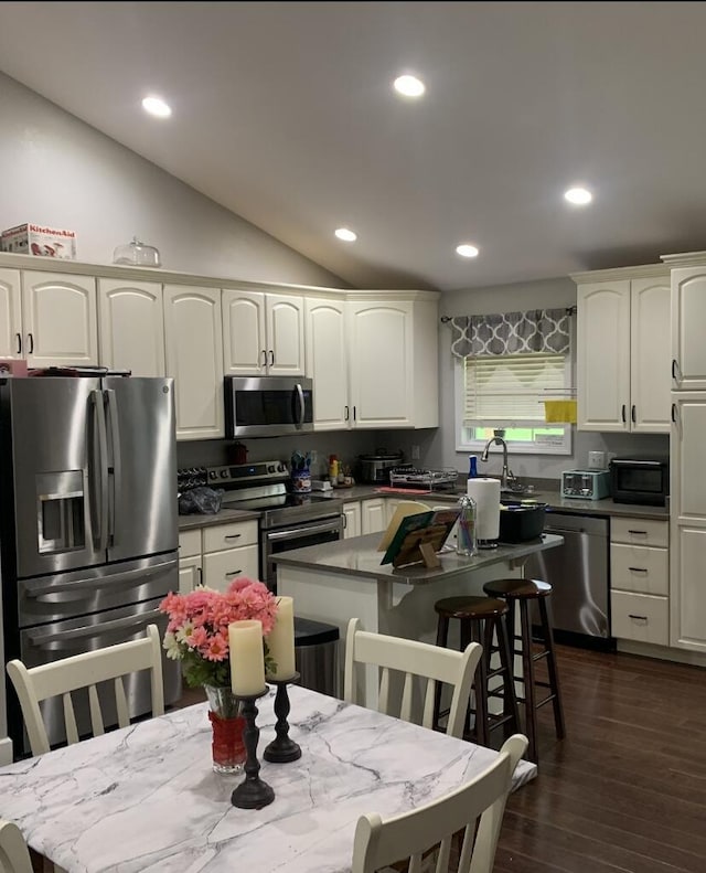 kitchen featuring white cabinetry, vaulted ceiling, recessed lighting, dark wood-type flooring, and appliances with stainless steel finishes