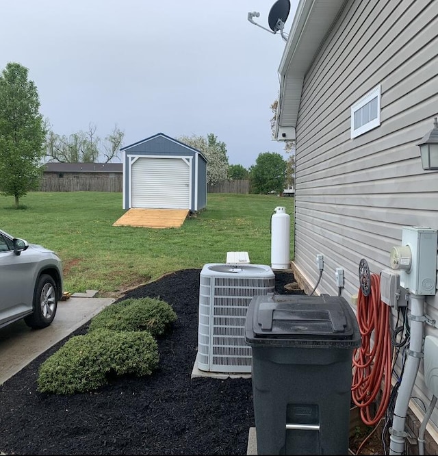 view of yard featuring fence, central AC, an outdoor structure, and a storage shed