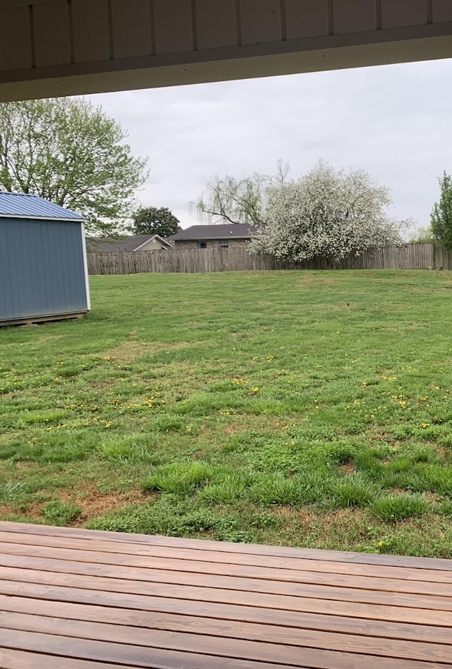 view of yard featuring a fenced backyard, a shed, and an outbuilding