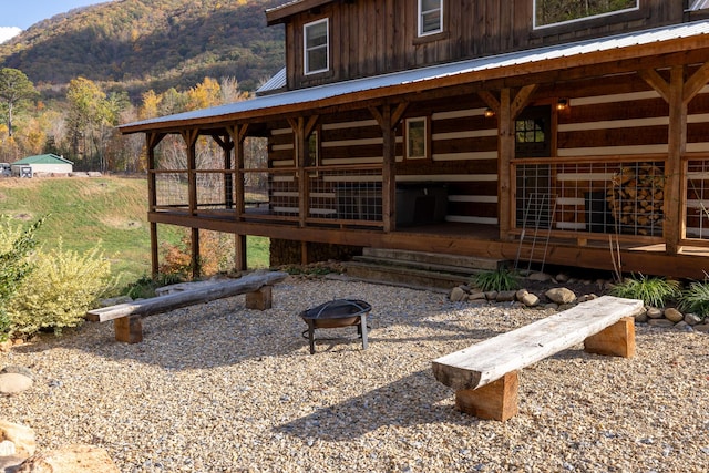 rear view of property with a mountain view and an outdoor fire pit