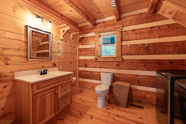 bathroom with beam ceiling, wooden ceiling, wood walls, toilet, and vanity