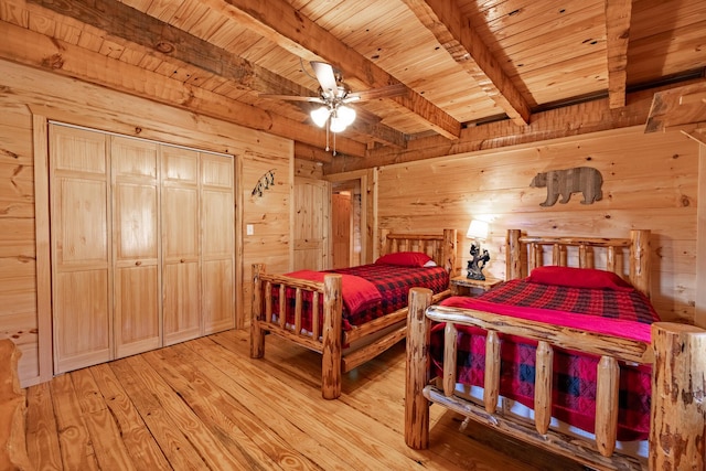 bedroom featuring beam ceiling, ceiling fan, wooden walls, and wood ceiling