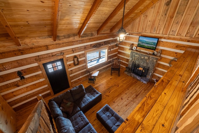 living room with hardwood / wood-style floors, wood walls, wooden ceiling, a stone fireplace, and beamed ceiling