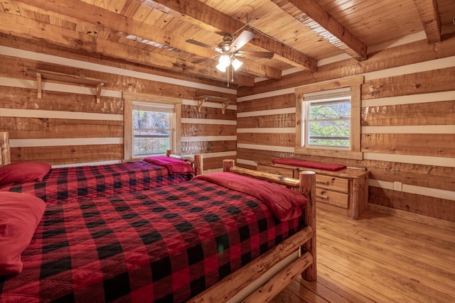 bedroom featuring beamed ceiling, ceiling fan, wood walls, and wood ceiling