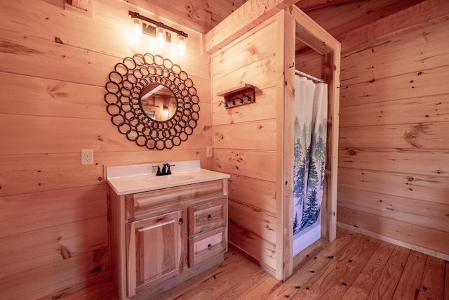 bathroom with wood walls, vanity, wood-type flooring, and walk in shower