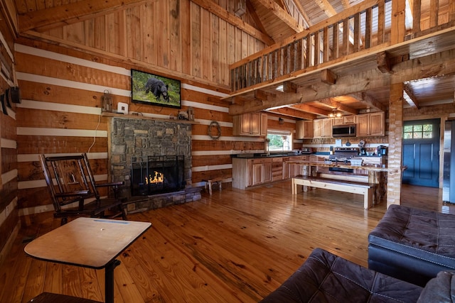 living room featuring beam ceiling, high vaulted ceiling, a fireplace, wood ceiling, and light wood-type flooring