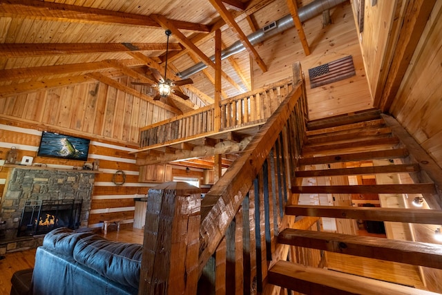 interior space with high vaulted ceiling, a stone fireplace, wooden walls, beamed ceiling, and wood ceiling