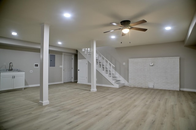 basement featuring electric panel, light hardwood / wood-style flooring, ceiling fan, and sink