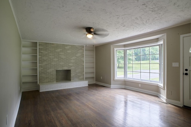 unfurnished living room with ceiling fan, a brick fireplace, built in features, dark hardwood / wood-style floors, and a textured ceiling