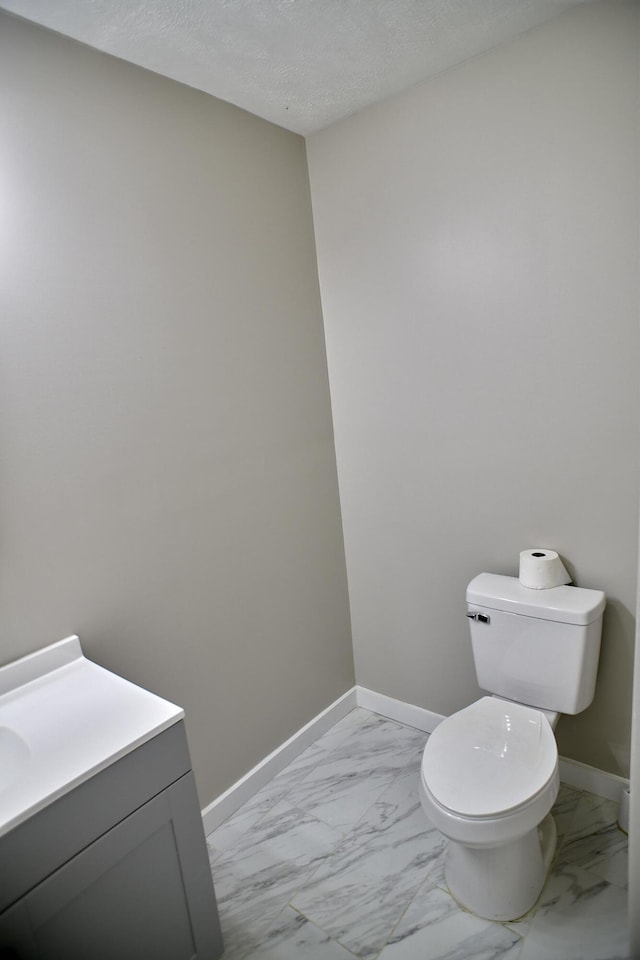 bathroom with vanity, toilet, and a textured ceiling