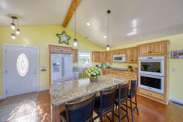 kitchen with vaulted ceiling with beams, white appliances, dark wood-type flooring, decorative light fixtures, and a center island