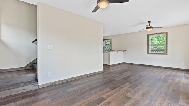 unfurnished living room with dark wood-type flooring, ceiling fan, and a wealth of natural light