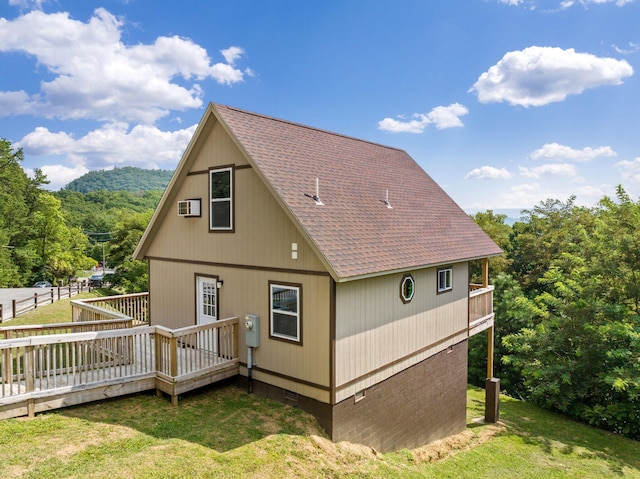 rear view of house featuring a deck, a lawn, and an AC wall unit