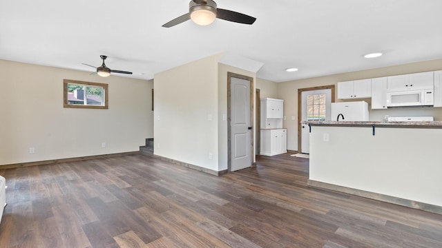 kitchen featuring dark wood-type flooring, white cabinetry, fridge, a kitchen breakfast bar, and kitchen peninsula