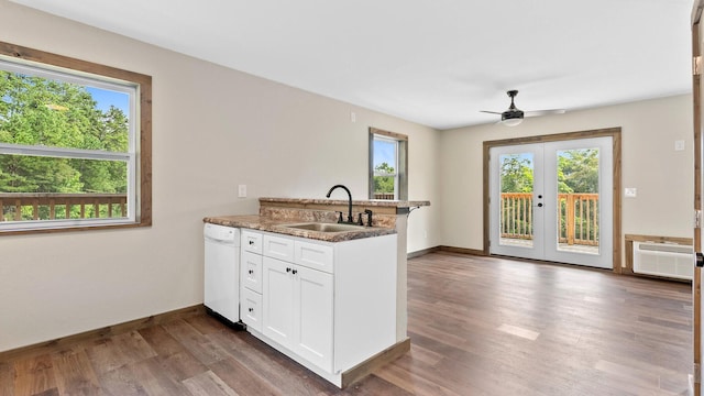 kitchen with sink, dishwasher, kitchen peninsula, dark stone counters, and white cabinets