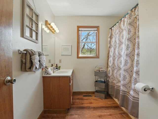 full bathroom featuring vanity, visible vents, wood finished floors, and baseboards
