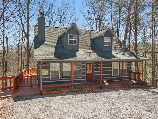 view of front of property featuring a porch, roof with shingles, and a chimney