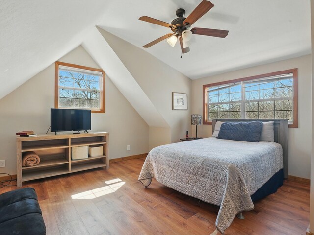 bedroom with vaulted ceiling, multiple windows, and wood finished floors