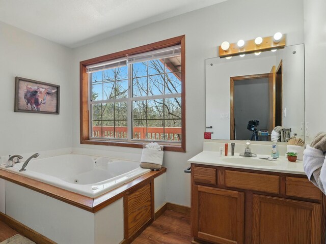 bathroom featuring vanity, a jetted tub, wood finished floors, and baseboards