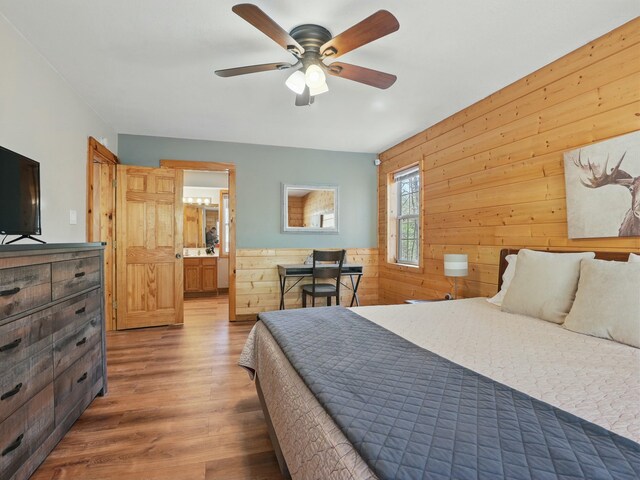 bedroom with ensuite bath, wood finished floors, and wood walls
