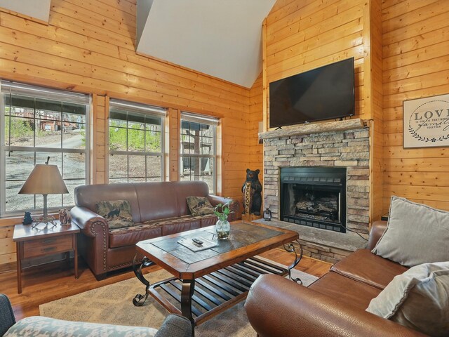 living area with a fireplace, wooden walls, wood finished floors, and high vaulted ceiling