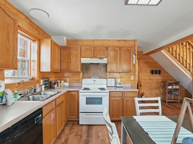 kitchen featuring under cabinet range hood, wood walls, black dishwasher, electric range, and a sink