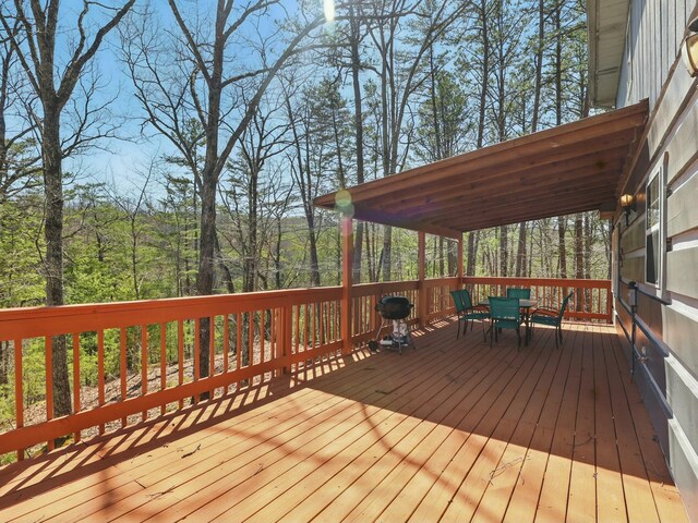 deck featuring a forest view and outdoor dining space