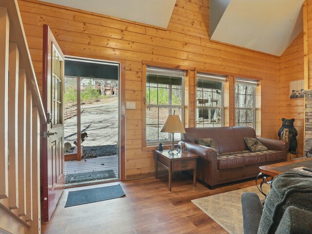 doorway with plenty of natural light, wooden walls, and vaulted ceiling
