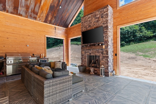 interior space with wooden walls, an outdoor stone fireplace, and high vaulted ceiling